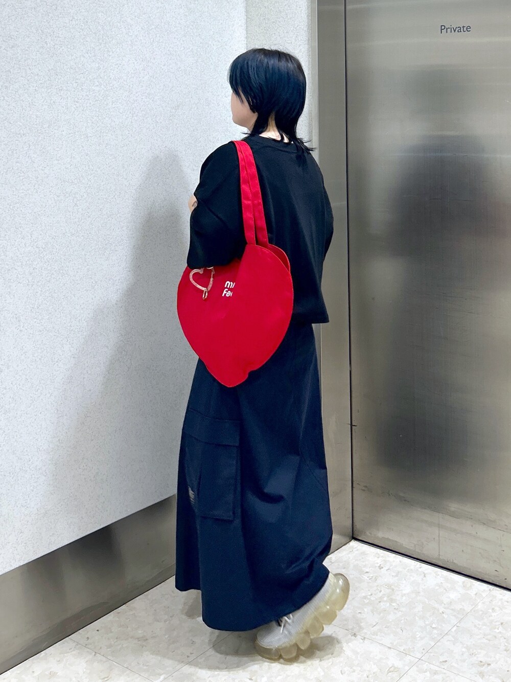 ブルー系のスカート、ブラック系のTシャツ/カットソー、レッド系のトートバッグを着用したレディースの夏コーディネートの6枚目の写真