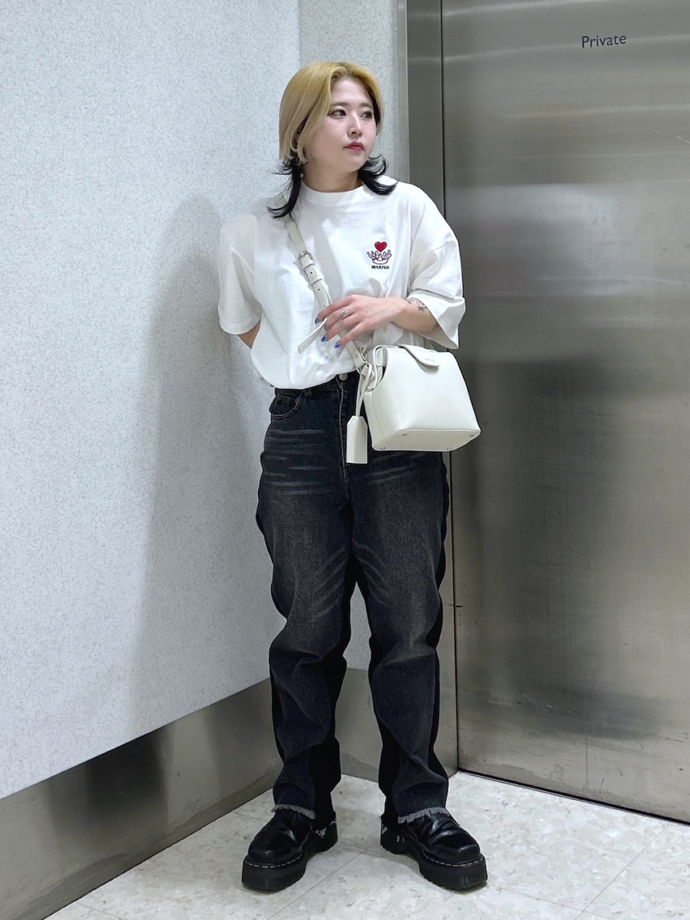 ブラック系のデニムパンツ、ホワイト系のショルダーバッグ、ブラック系のブーツを着用したレディースの春コーディネートの2枚目の写真