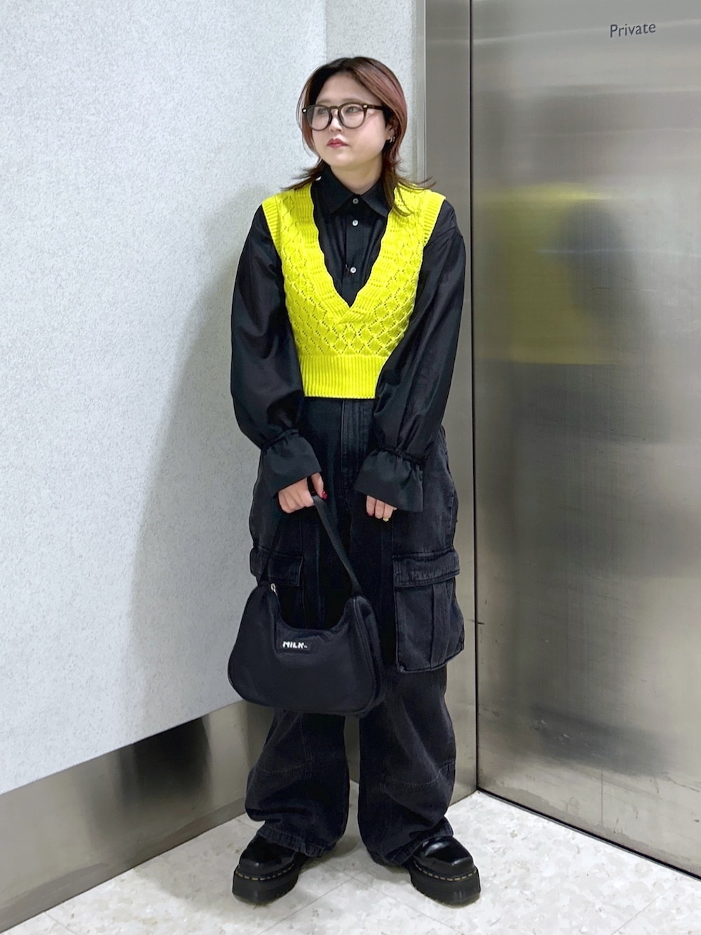 ブラック系のシャツ/ブラウス、イエロー系のベスト、ブラック系のカーゴパンツを着用したレディースの春コーディネートの2枚目の写真