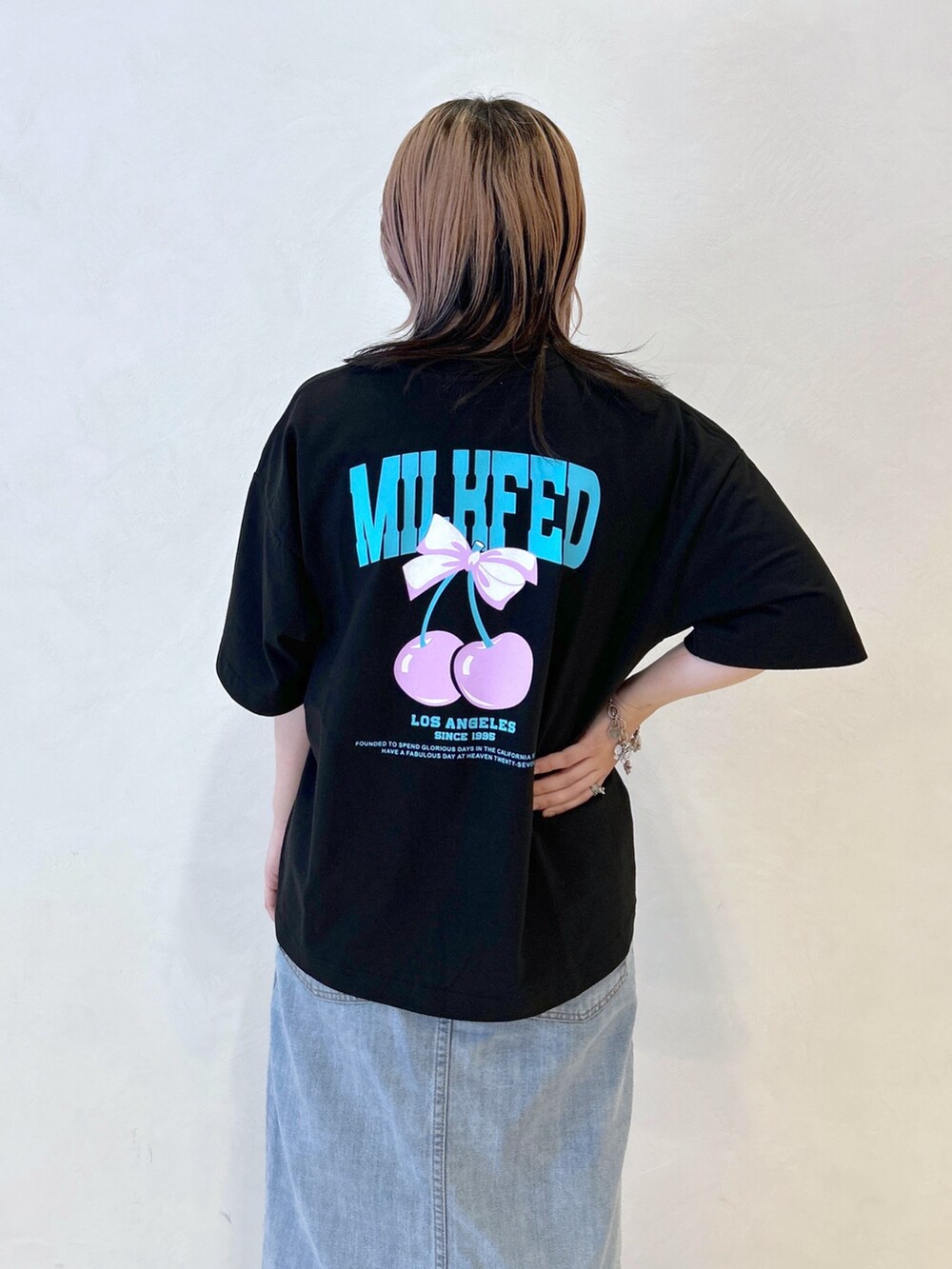 ブラック系のTシャツ/カットソー、ブルー系のデニムスカート、レッド系のトートバッグを着用したレディースの夏コーディネートの6枚目の写真