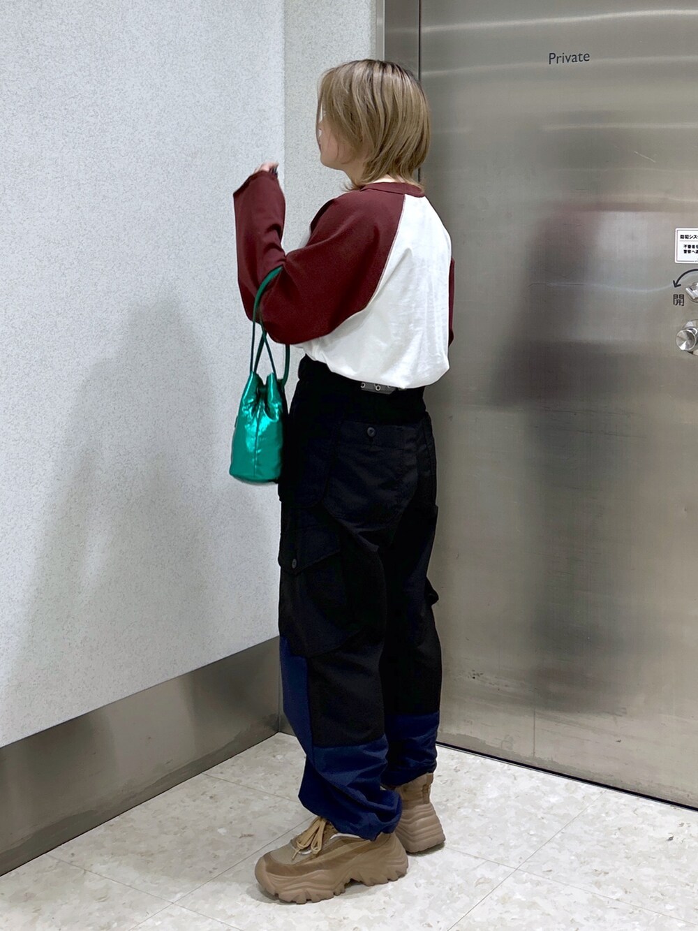 ブラウン系のTシャツ/カットソー、ブラック系のカーゴパンツ、グリーン系のショルダーバッグを着用したレディースの冬コーディネートの2枚目の写真