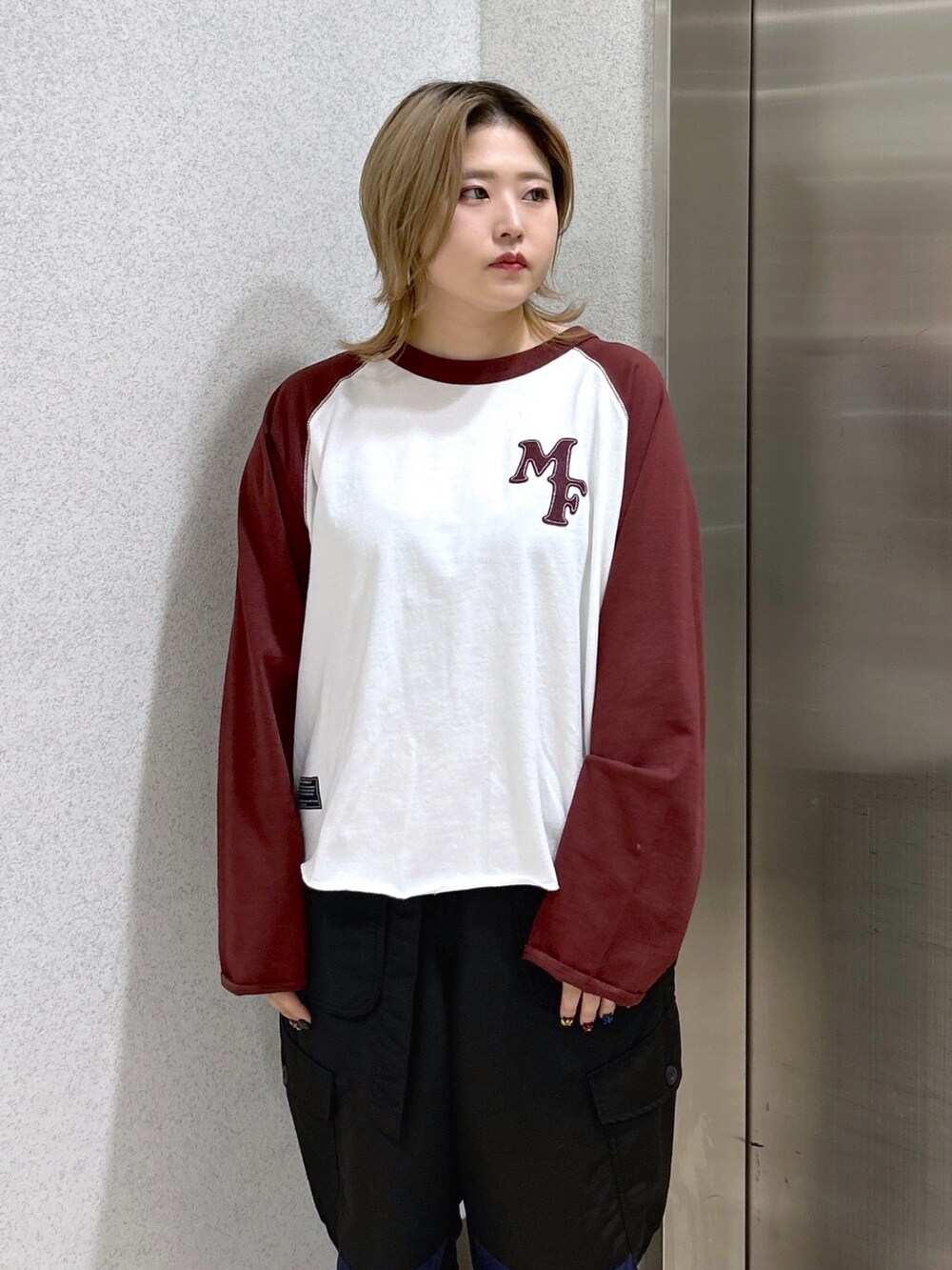 ブラウン系のTシャツ/カットソー、ブラック系のカーゴパンツ、グリーン系のショルダーバッグを着用したレディースの冬コーディネートの4枚目の写真