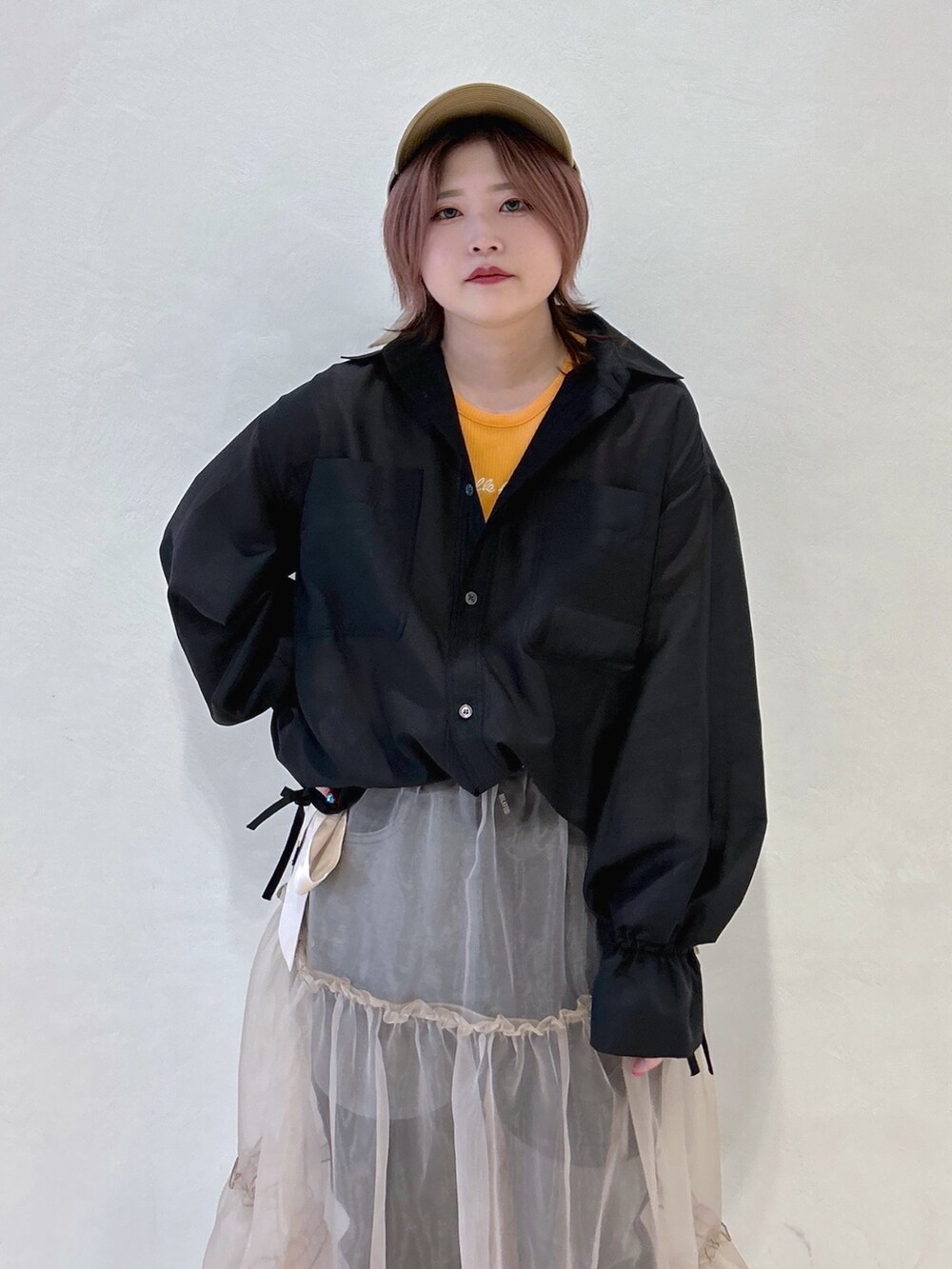 オレンジ系のTシャツ/カットソー、ブラック系のシャツ/ブラウス、ベージュ系のスカートを着用したレディースの冬コーディネートの4枚目の写真