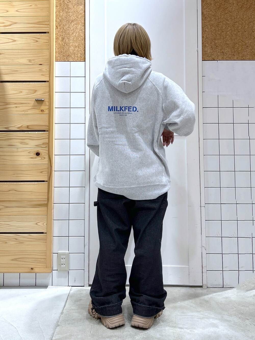 グレー系のパーカー、ブラック系のサロペット/オーバーオール、ベージュ系のスニーカーを着用したレディースの秋コーディネートの4枚目の写真