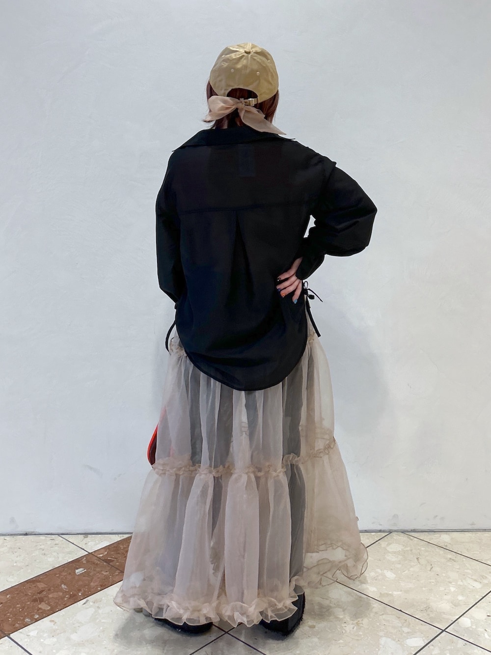 オレンジ系のTシャツ/カットソー、ブラック系のシャツ/ブラウス、ベージュ系のスカートを着用したレディースの冬コーディネートの3枚目の写真