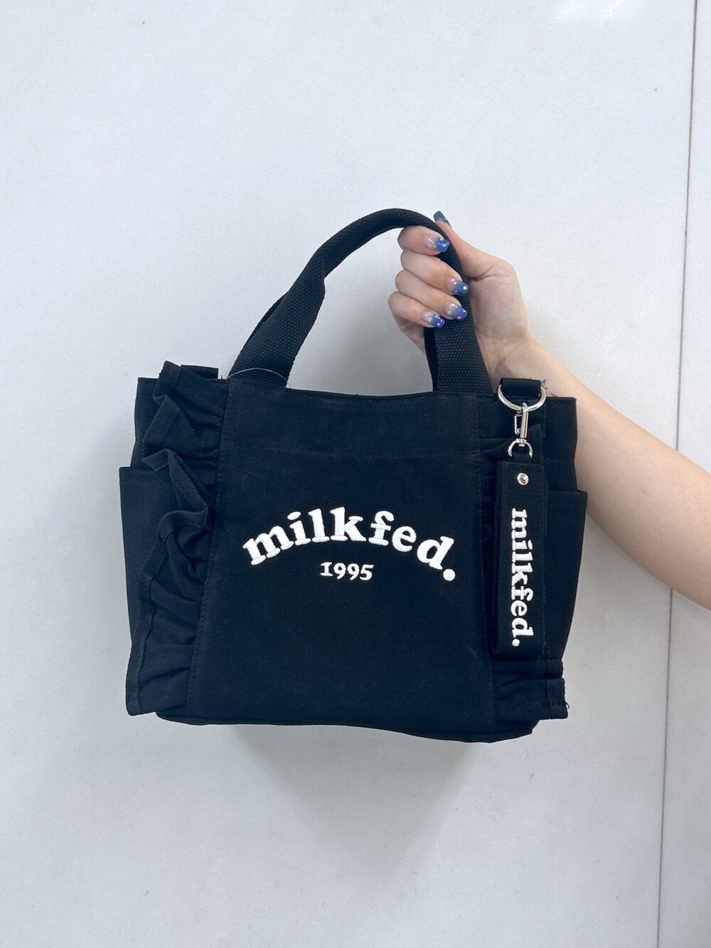 ホワイト系のワンピース、ブラック系のショルダーバッグ、ブラック系のブーツを着用したレディースの夏コーディネートの6枚目の写真