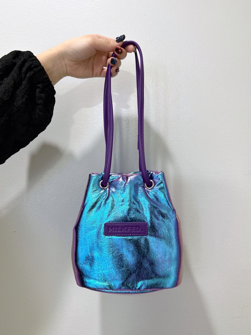 ブラック系のワンピース、パープル系のショルダーバッグ、ベージュ系のスニーカーを着用したレディースの冬コーディネートの4枚目の写真