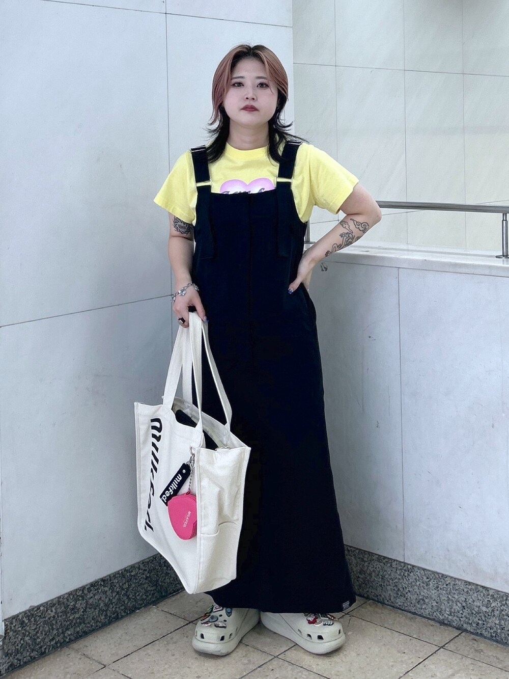 イエロー系のTシャツ/カットソー、ブラック系のワンピース、ホワイト系のショルダーバッグを着用したレディースの夏コーディネートの2枚目の写真