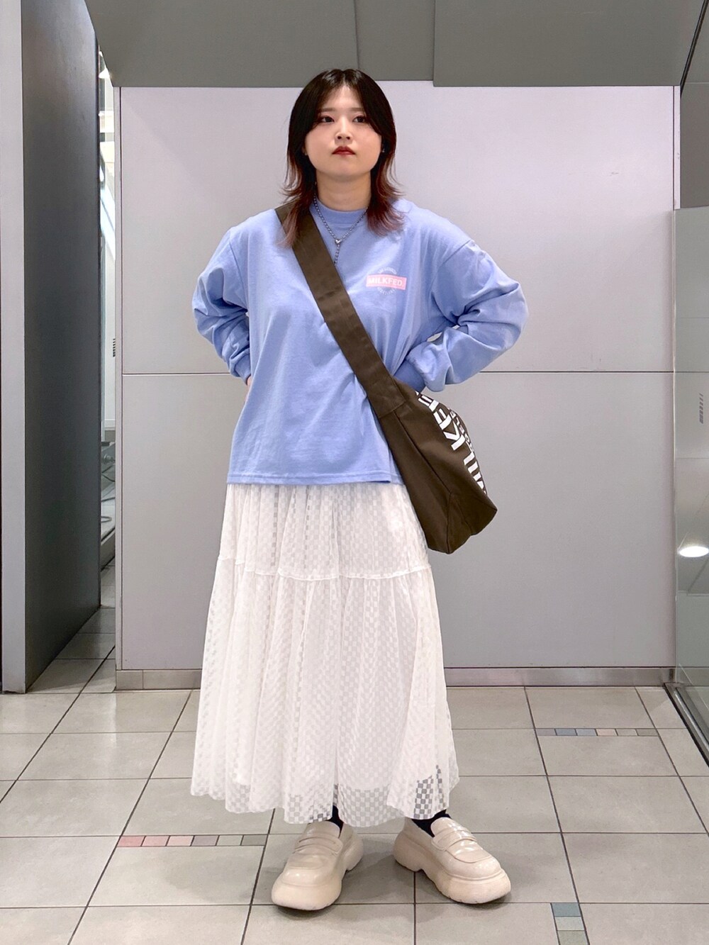 ブルー系のTシャツ/カットソー、ブラウン系のショルダーバッグ、ホワイト系のスカートを着用したレディースの夏コーディネートの2枚目の写真