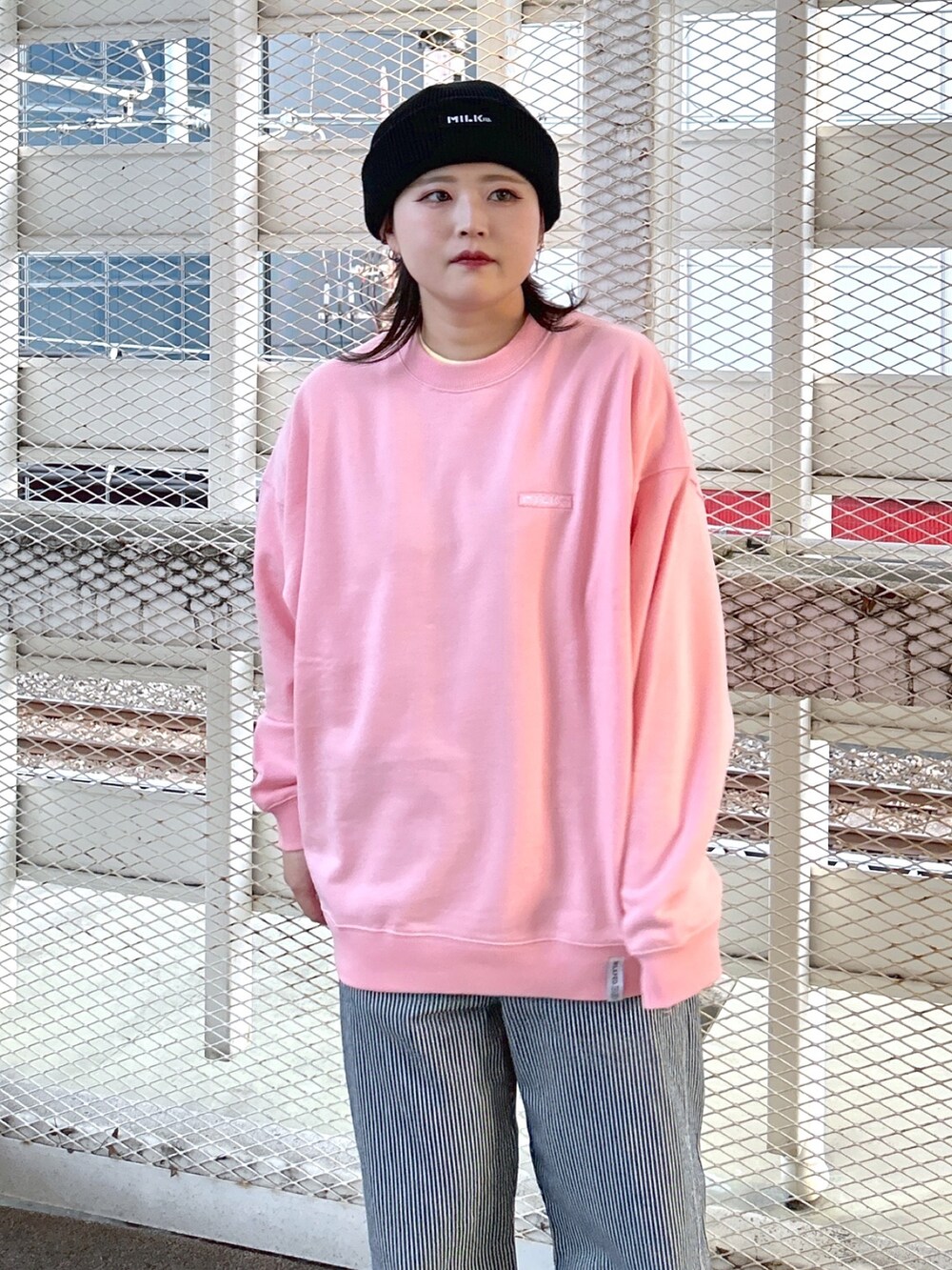 ピンク系のスウェット、ブラック系のショルダーバッグ、ブラック系のブーツを着用したレディースの冬コーディネートの4枚目の写真