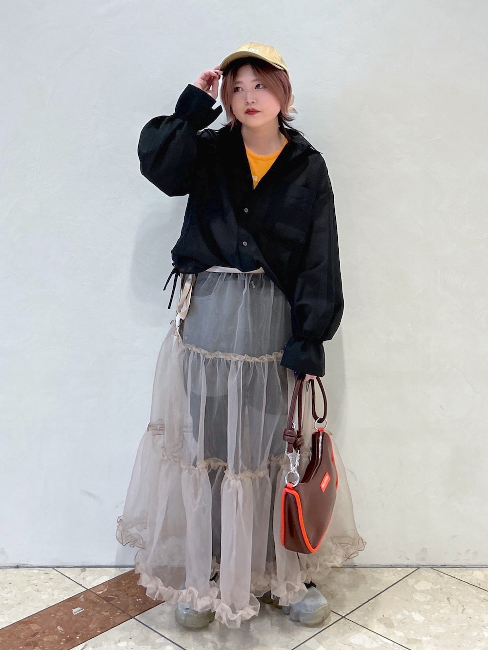 オレンジ系のTシャツ/カットソー、ブラック系のシャツ/ブラウス、ベージュ系のスカートを着用したレディースの冬コーディネートの2枚目の写真