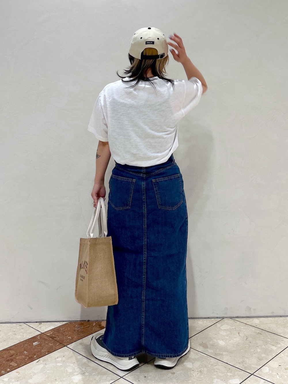 ホワイト系のTシャツ/カットソー、ブルー系のデニムスカート、ベージュ系のトートバッグを着用したレディースの春コーディネートの3枚目の写真