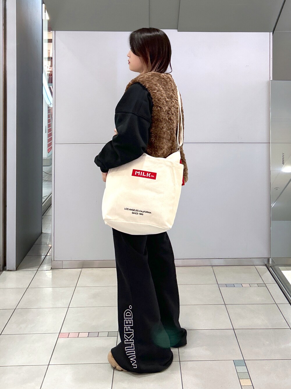 ブラウン系のベスト、ブラック系のTシャツ/カットソー、その他のトートバッグを着用したレディースの秋コーディネートの2枚目の写真