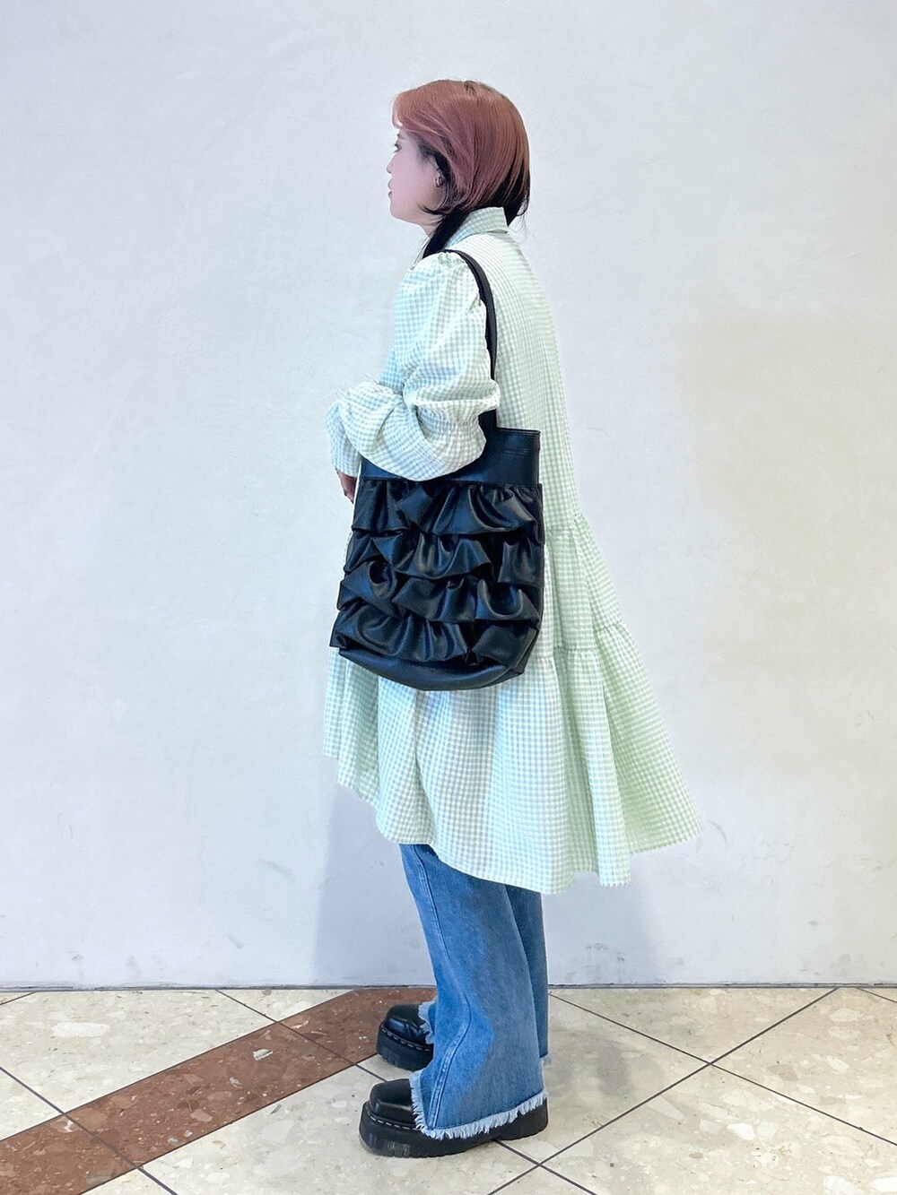 グリーン系のワンピース、ブルー系のデニムパンツ、ブラック系のトートバッグを着用したレディースの夏コーディネートの3枚目の写真