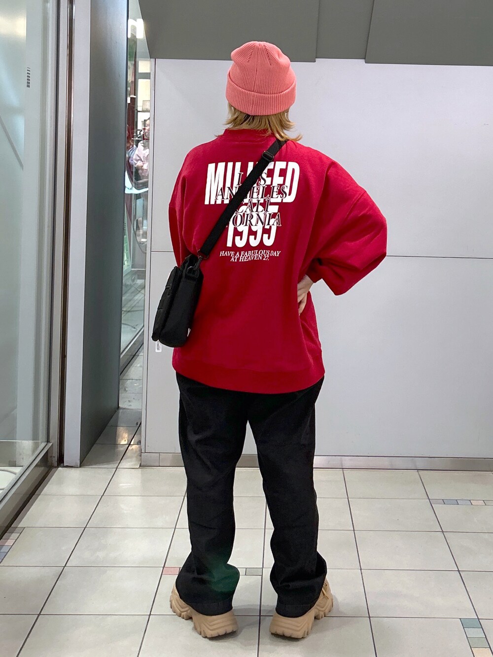 レッド系のスウェット、ピンク系のショルダーバッグ、ブラック系のデニムパンツを着用したレディースの秋コーディネートの3枚目の写真