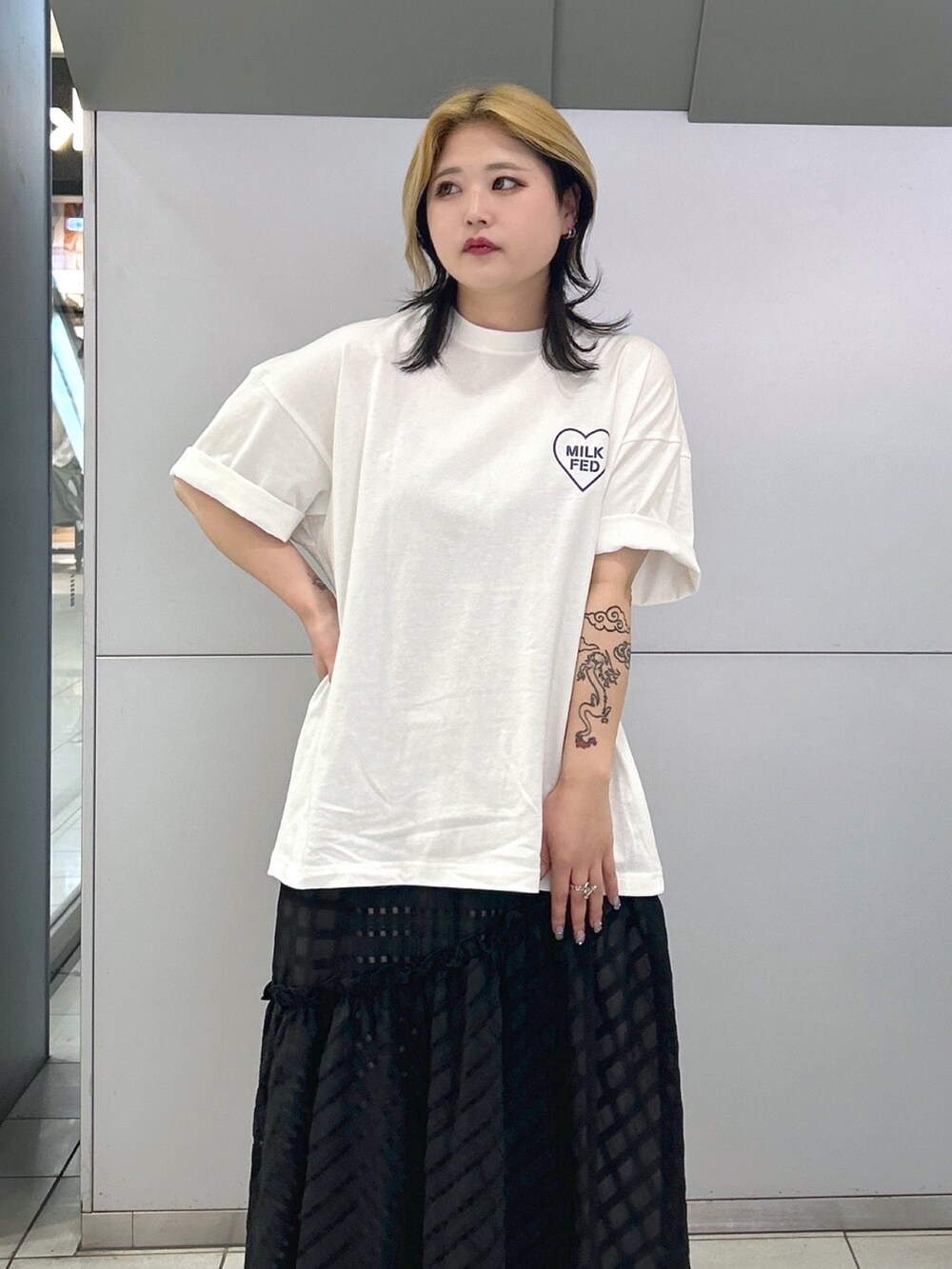 ホワイト系のTシャツ/カットソー、ブラック系のスカート、ブルー系のトートバッグを着用したレディースの春コーディネートの3枚目の写真