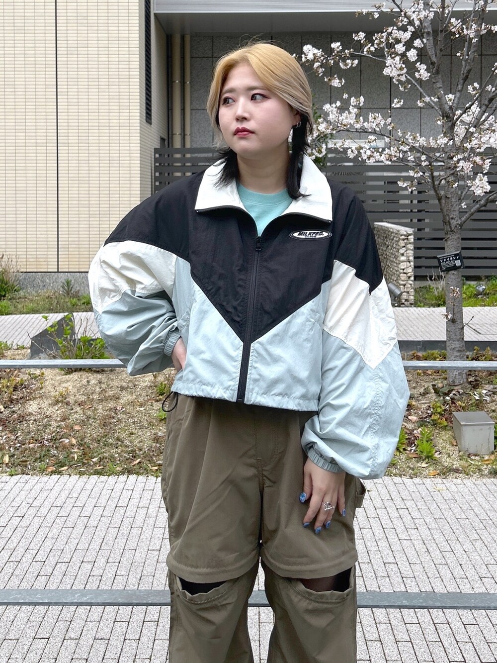 ブラック系のナイロンジャケット、グリーン系のTシャツ/カットソー、ブラック系のブーツを着用したレディースの春コーディネートの5枚目の写真