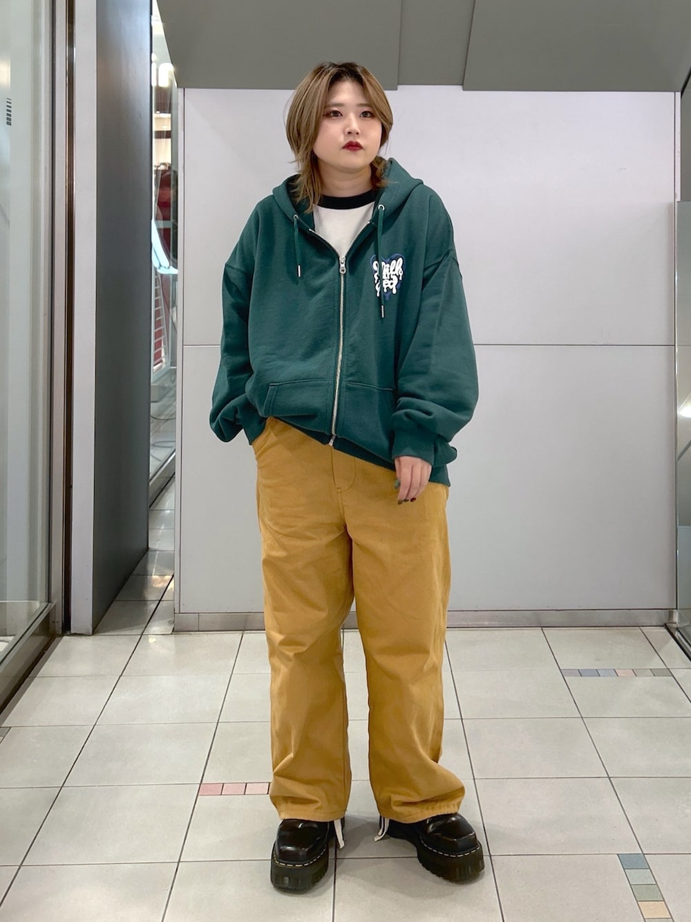 グリーン系のパーカー、ブラック系のTシャツ/カットソー、ベージュ系のサロペット/オーバーオールを着用したレディースの冬コーディネートの2枚目の写真