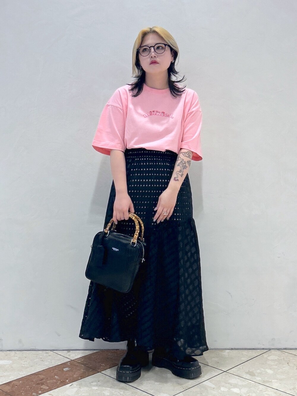 ブラック系のブーツ、ブラック系のスカート、ブラック系のショルダーバッグを着用したレディースの春コーディネートの3枚目の写真