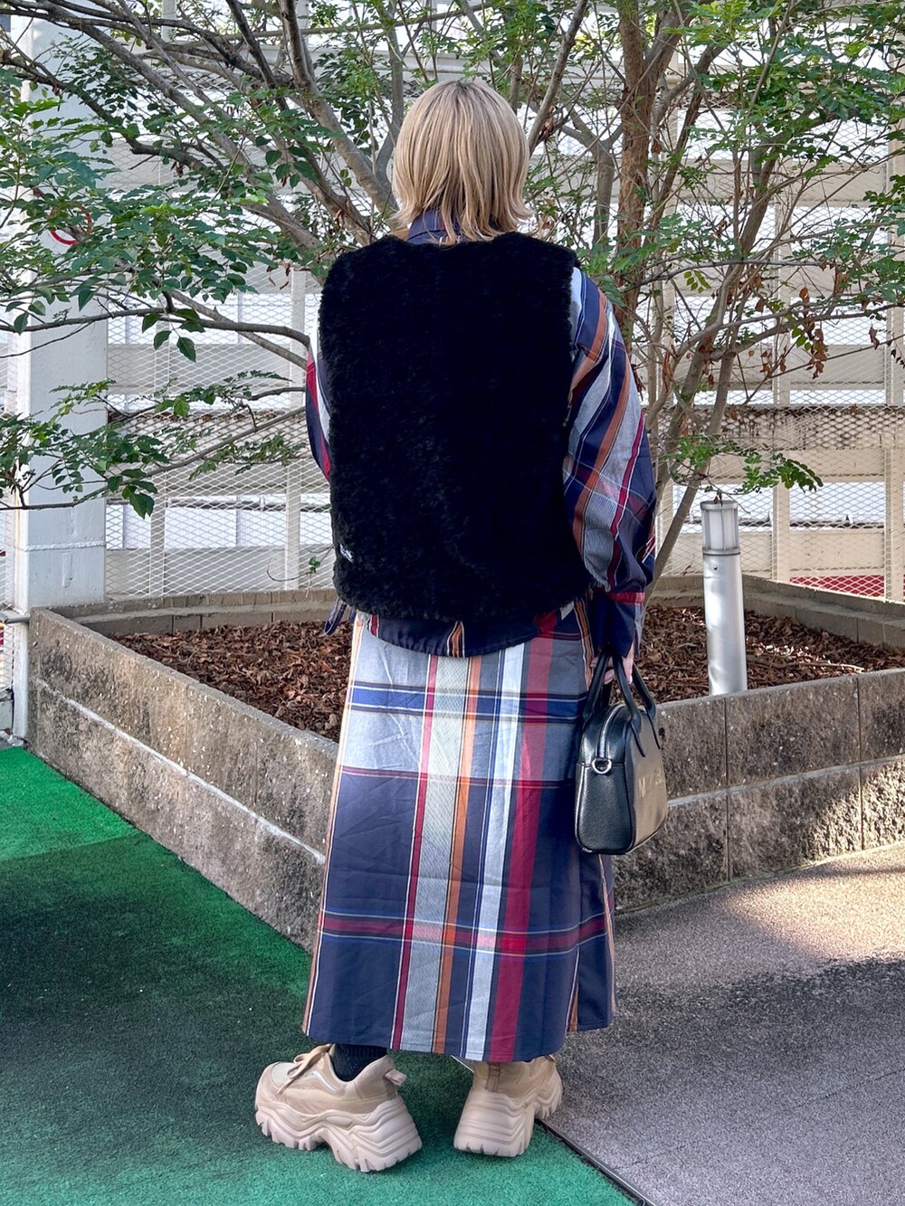 ブラック系のベスト、ブルー系のシャツ/ブラウス、ブルー系のスカートを着用したレディースの秋コーディネートの2枚目の写真