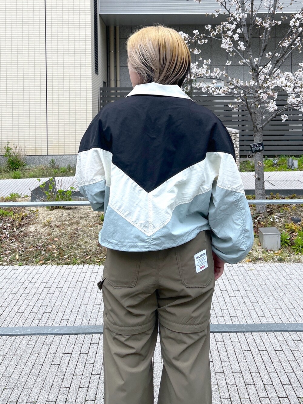 ブラック系のナイロンジャケット、グリーン系のTシャツ/カットソー、ブラック系のブーツを着用したレディースの春コーディネートの6枚目の写真