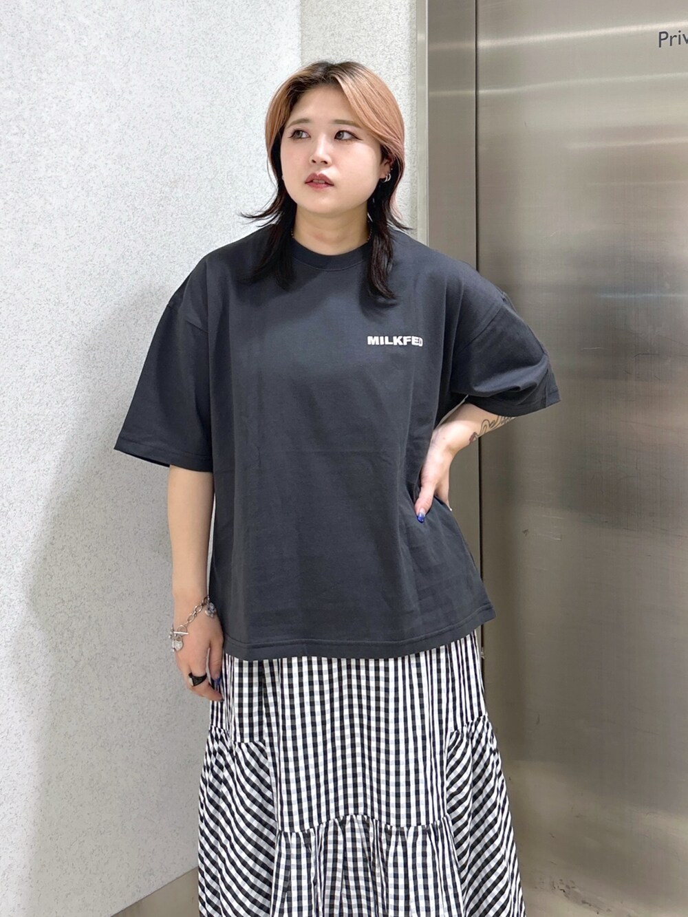 グレー系のTシャツ/カットソー、ブラック系のスカート、ホワイト系のショルダーバッグを着用したレディースの夏コーディネートの4枚目の写真