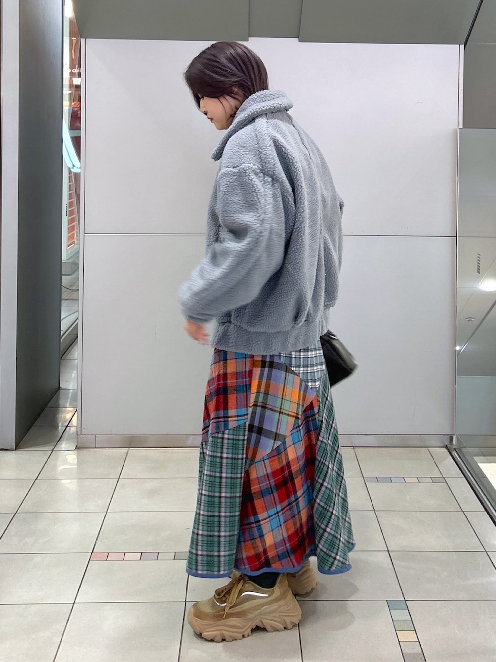 ブラック系のボストンバッグ、グリーン系のスカート、ベージュ系のスニーカーを着用したレディースの秋コーディネートの2枚目の写真