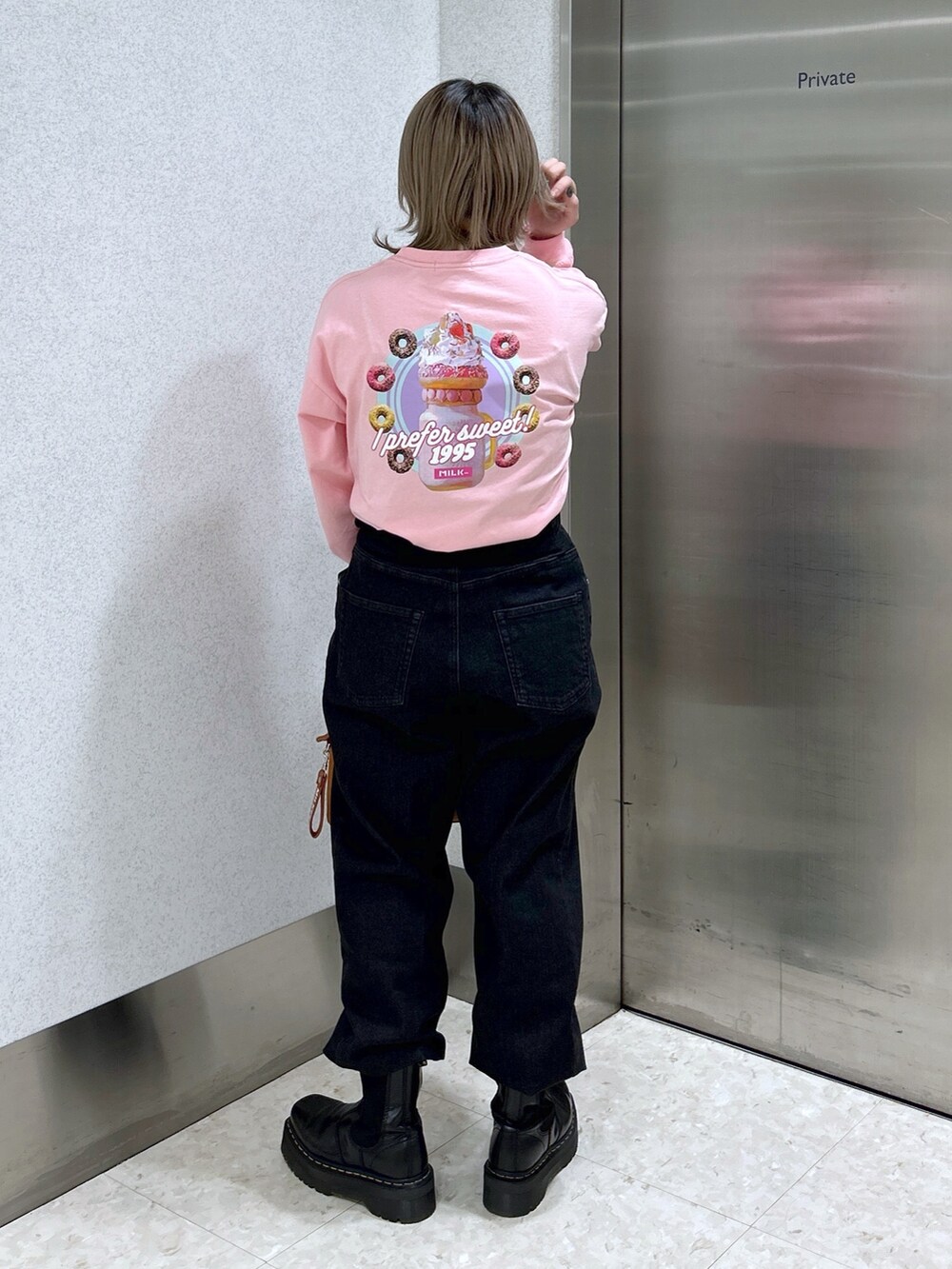 ピンク系のTシャツ/カットソー、ブラック系のデニムパンツ、ブラウン系のボストンバッグを着用したレディースの冬コーディネートの3枚目の写真