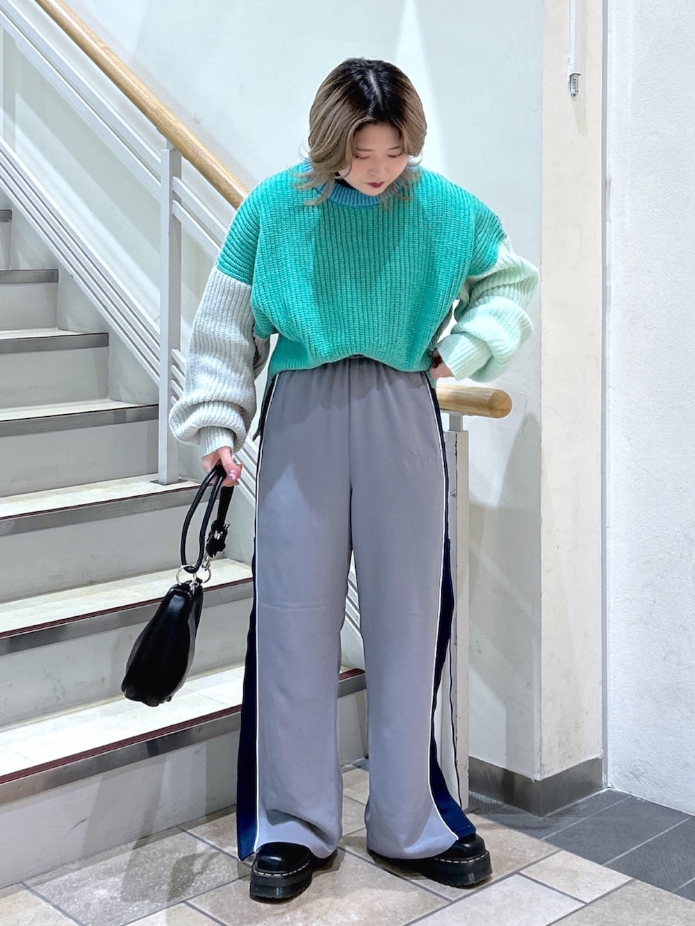 グリーン系のニット/セーター、ブラック系のショルダーバッグ、ブラック系のブーツを着用したレディースの冬コーディネートの2枚目の写真