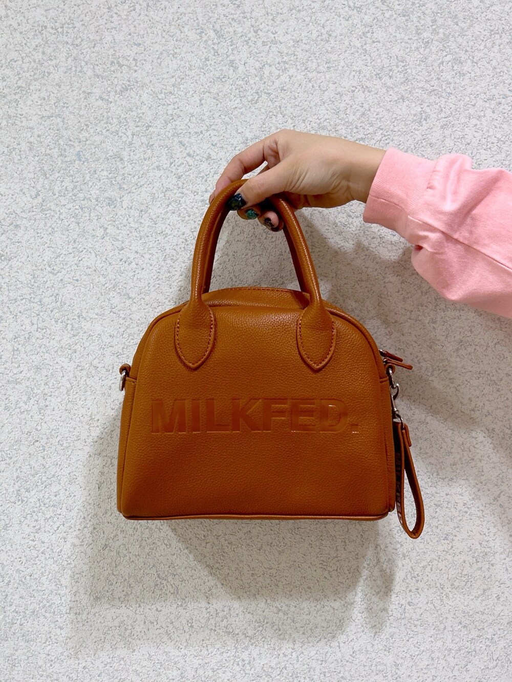 ピンク系のTシャツ/カットソー、ブラック系のデニムパンツ、ブラウン系のボストンバッグを着用したレディースの冬コーディネートの4枚目の写真