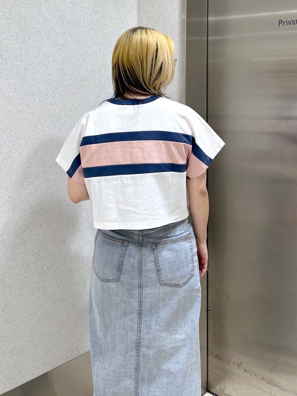 ホワイト系のTシャツ/カットソー、ブルー系のデニムスカート、ホワイト系のショルダーバッグを着用したレディースの春コーディネートの5枚目の写真