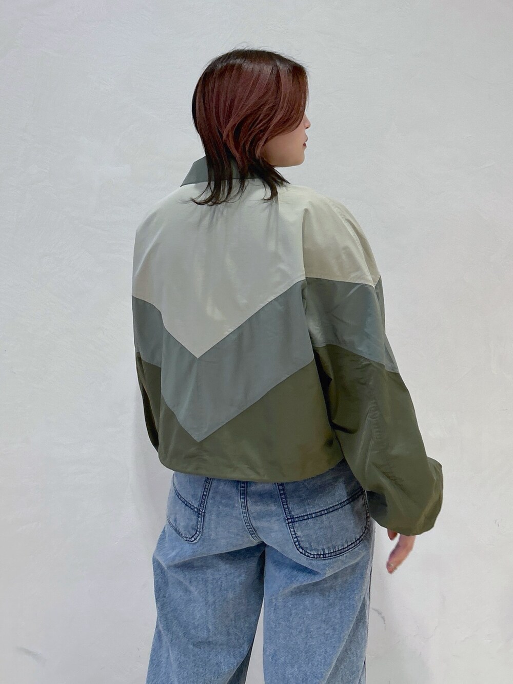 ブルー系のデニムパンツ、グリーン系のハンドバッグ、ブラック系のブーツを着用したレディースの冬コーディネートの8枚目の写真