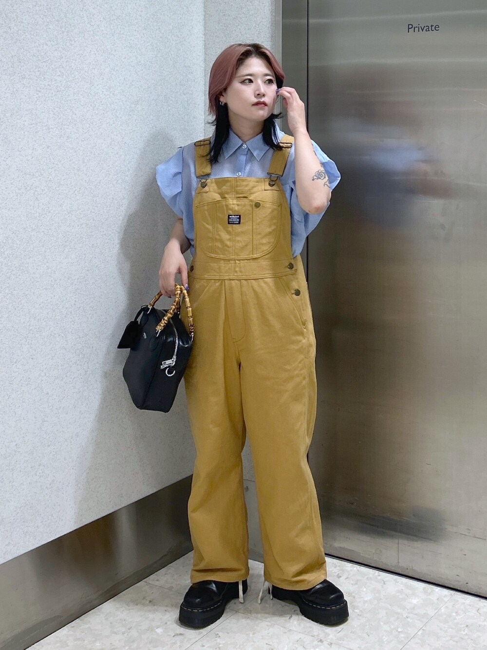 ブルー系のシャツ/ブラウス、ベージュ系のサロペット/オーバーオール、ブラック系のショルダーバッグを着用したレディースの夏コーディネートの3枚目の写真