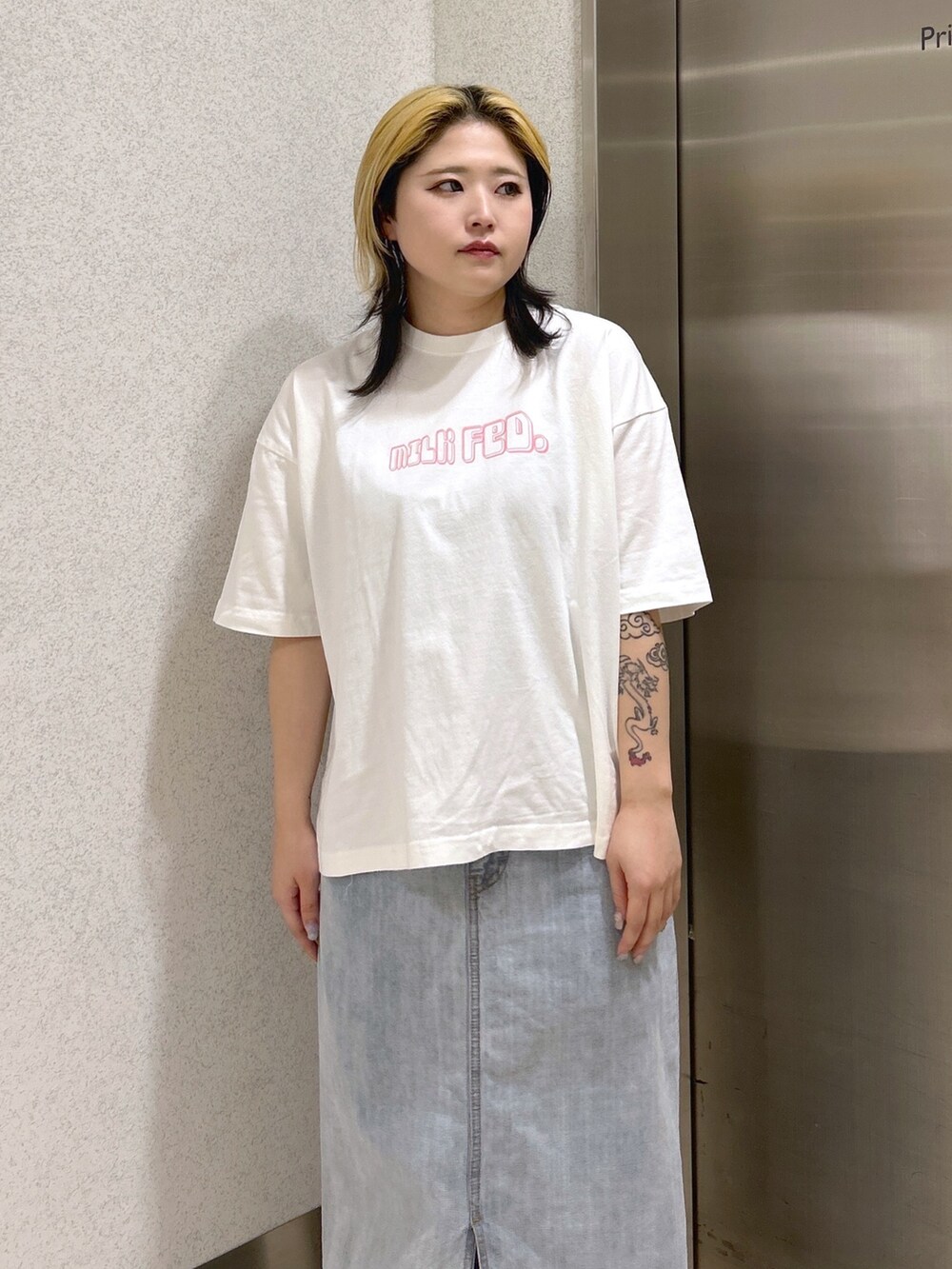 ホワイト系のTシャツ/カットソー、ブルー系のデニムスカート、グリーン系のバックパック/リュックを着用したレディースの春コーディネートの5枚目の写真