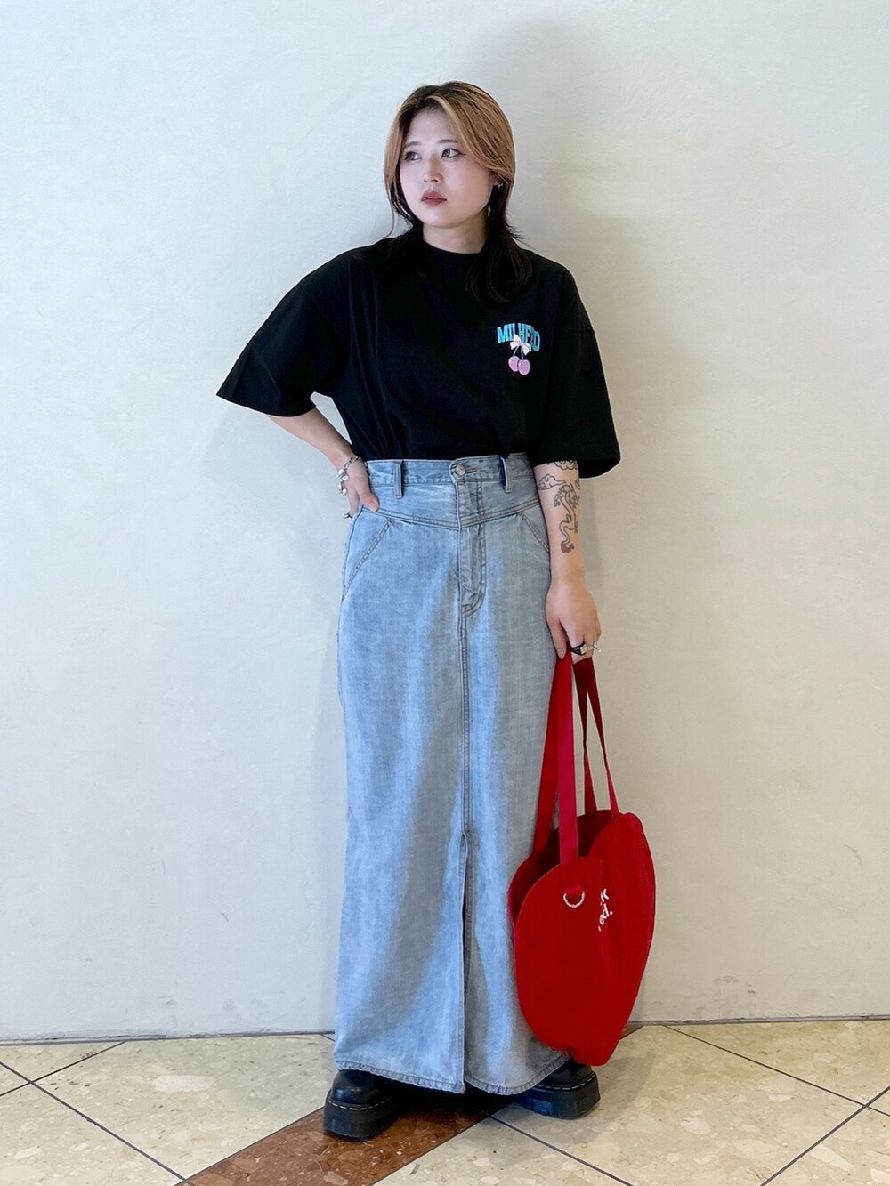 ブラック系のTシャツ/カットソー、ブルー系のデニムスカート、レッド系のトートバッグを着用したレディースの夏コーディネートの3枚目の写真