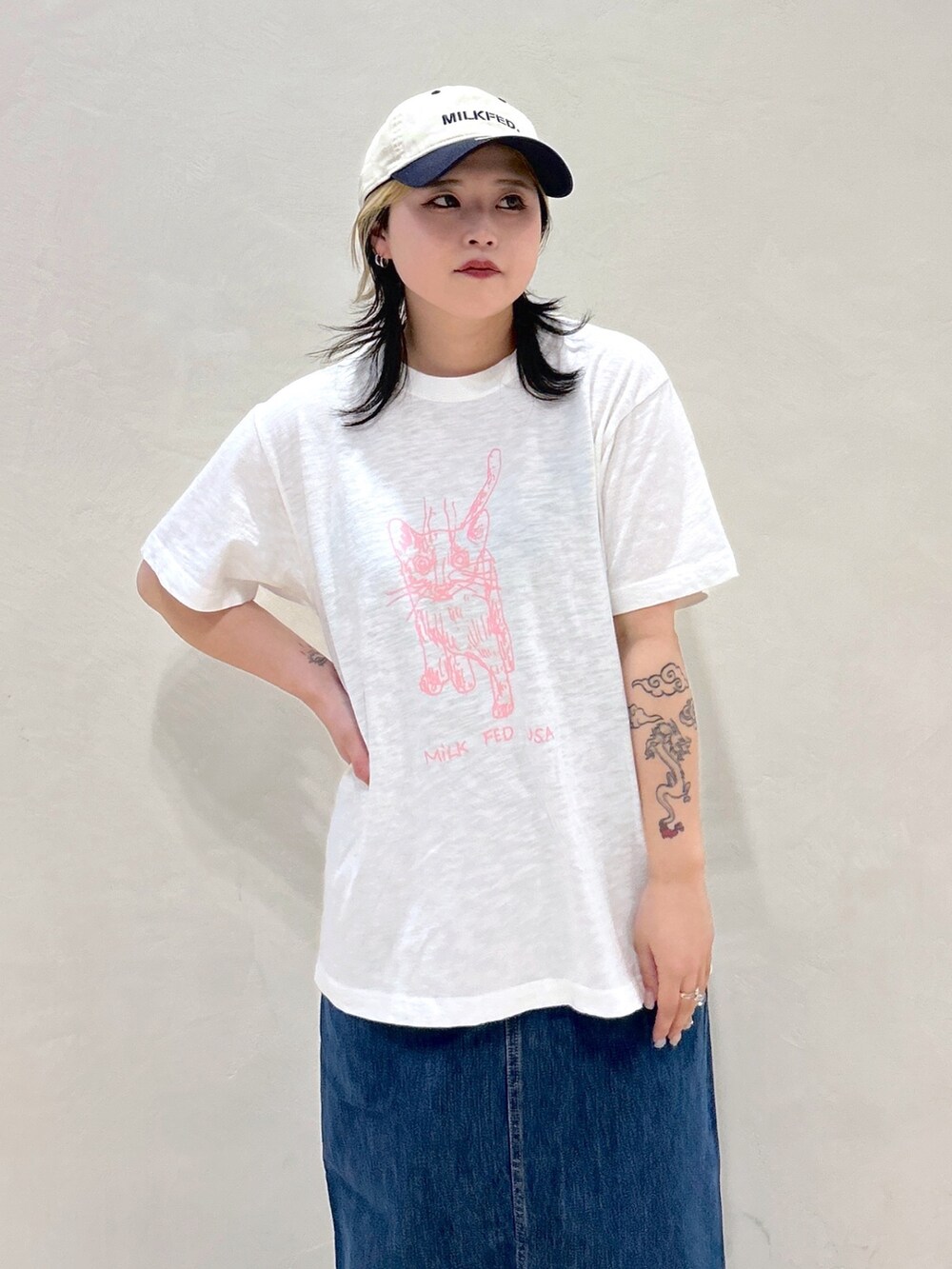 ホワイト系のTシャツ/カットソー、ブルー系のデニムスカート、ベージュ系のトートバッグを着用したレディースの春コーディネートの5枚目の写真