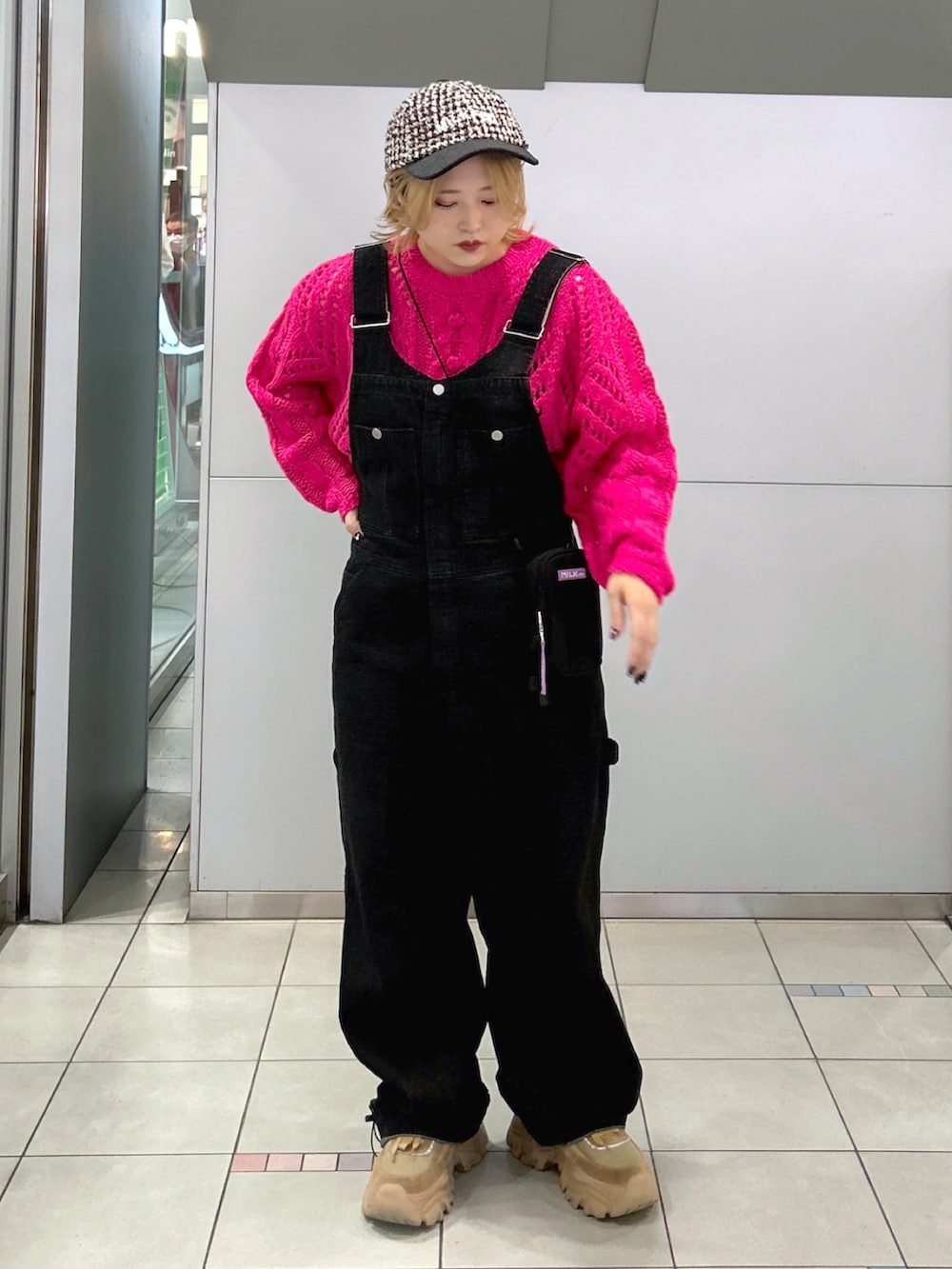 ピンク系のニット/セーター、ブラック系のサロペット/オーバーオール、パープル系のショルダーバッグを着用したレディースの秋コーディネートの2枚目の写真