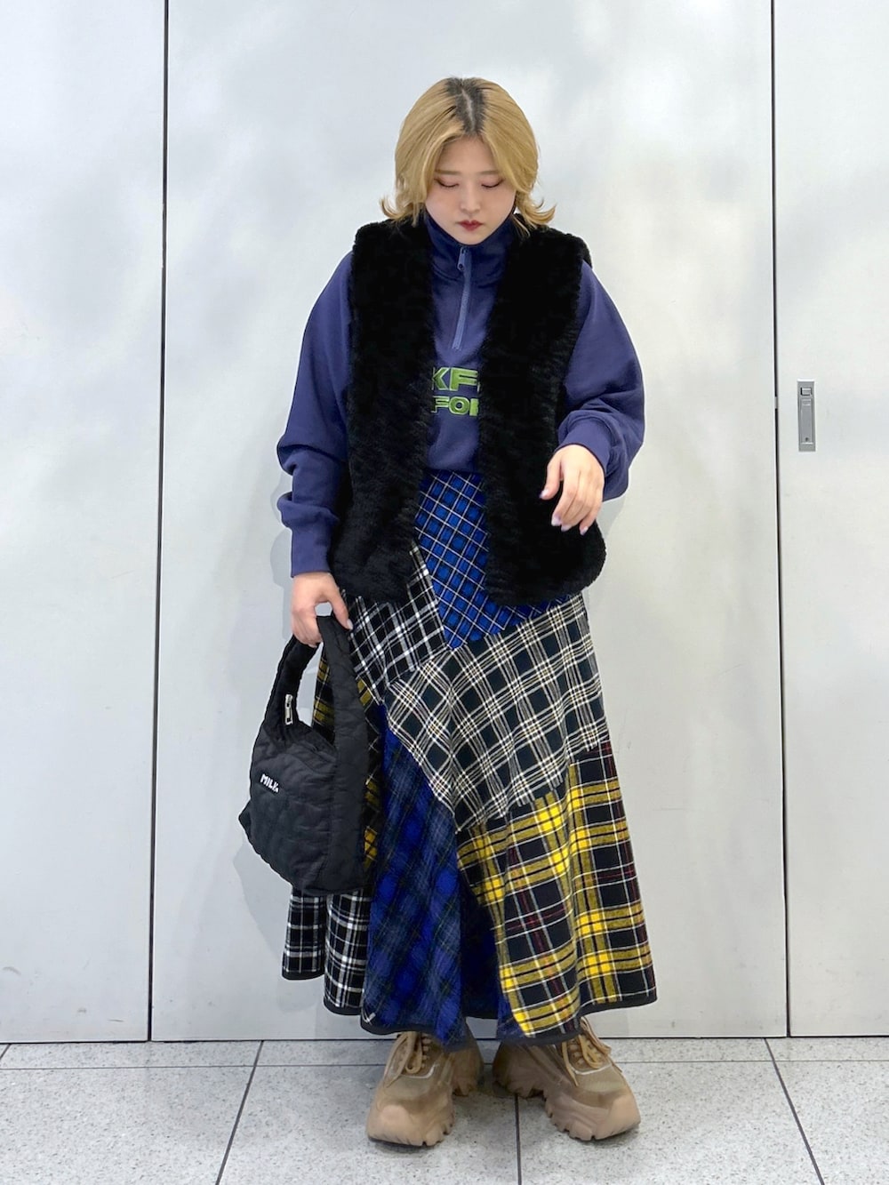 ブラック系のベスト、ブルー系のスウェット、ブラック系のスカートを着用したレディースの秋コーディネートの2枚目の写真