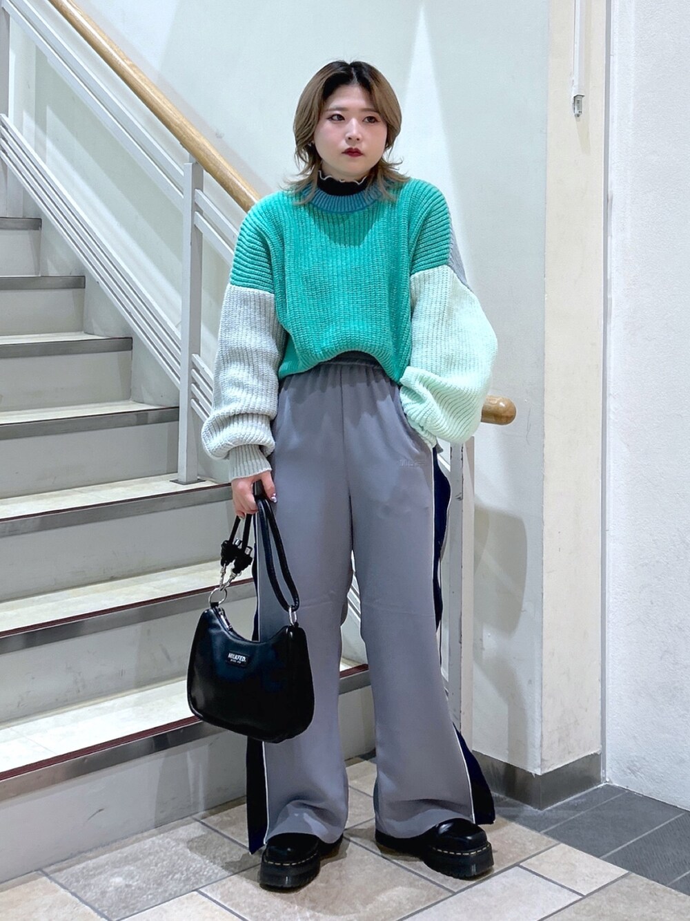 グリーン系のニット/セーター、ブラック系のショルダーバッグ、ブラック系のブーツを着用したレディースの冬コーディネートの3枚目の写真