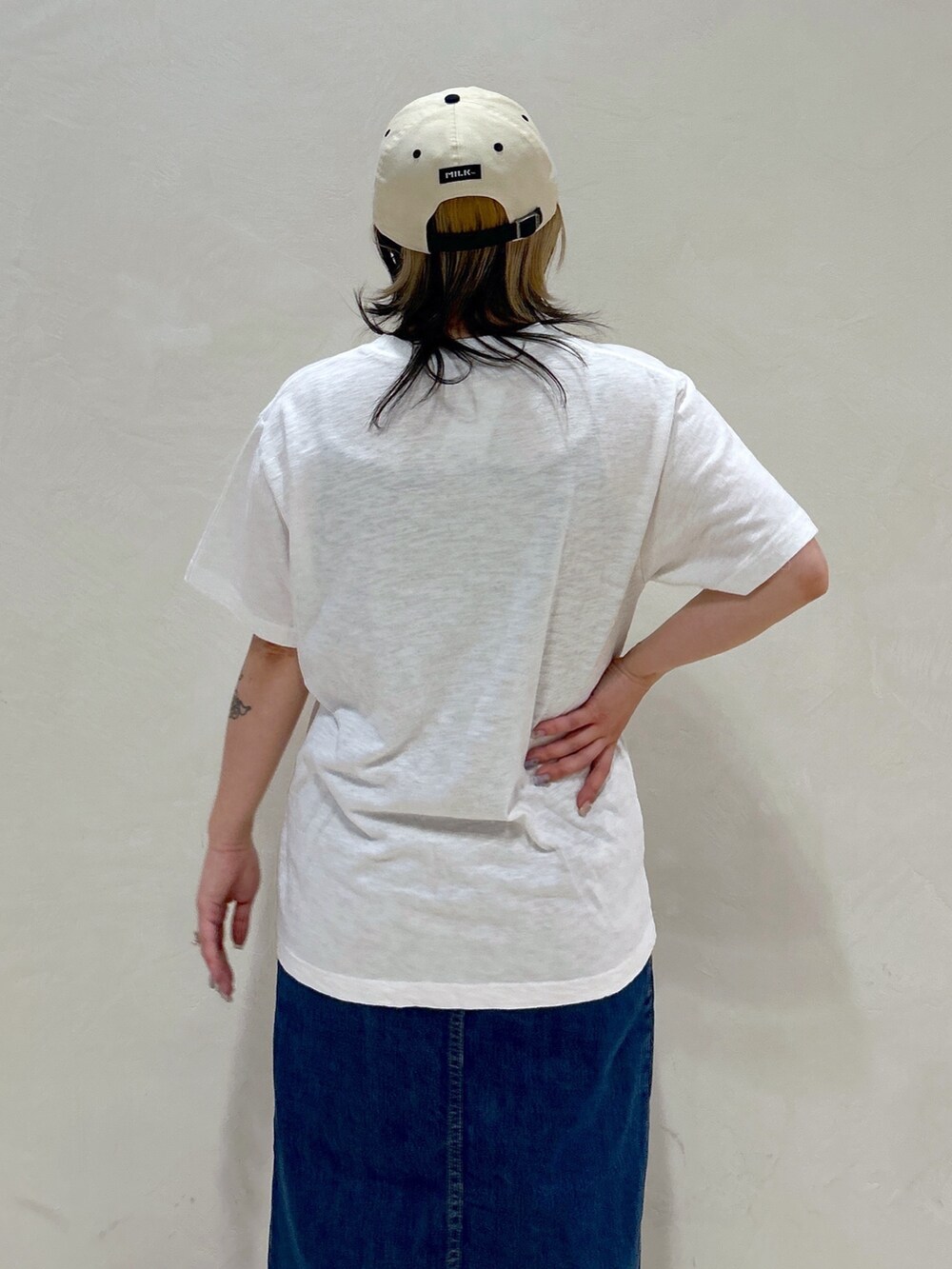 ホワイト系のTシャツ/カットソー、ブルー系のデニムスカート、ベージュ系のトートバッグを着用したレディースの春コーディネートの6枚目の写真