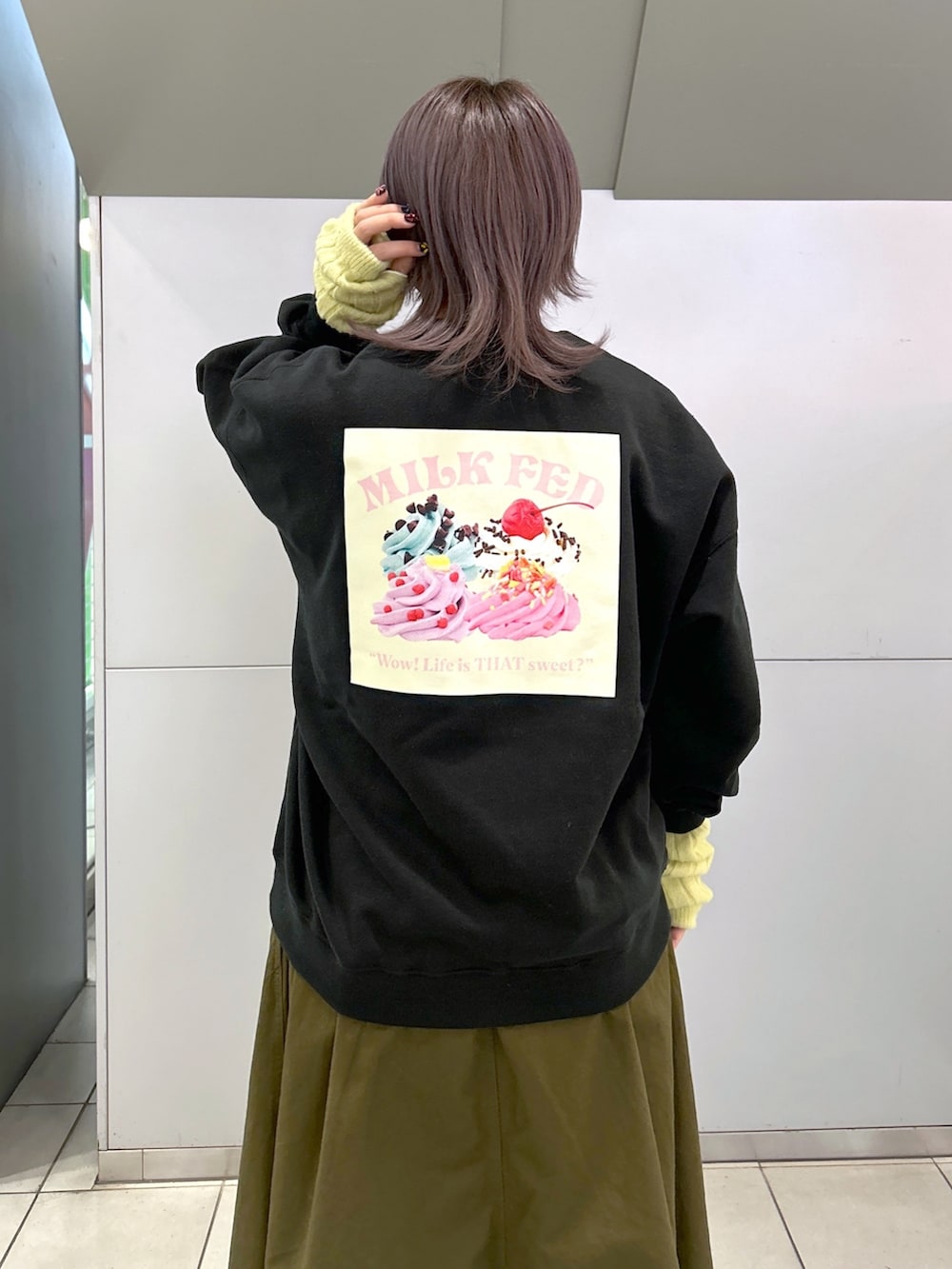 ブラック系のスウェット、グリーン系のジャンパースカート、シルバー系のショルダーバッグを着用したレディースの冬コーディネートの3枚目の写真