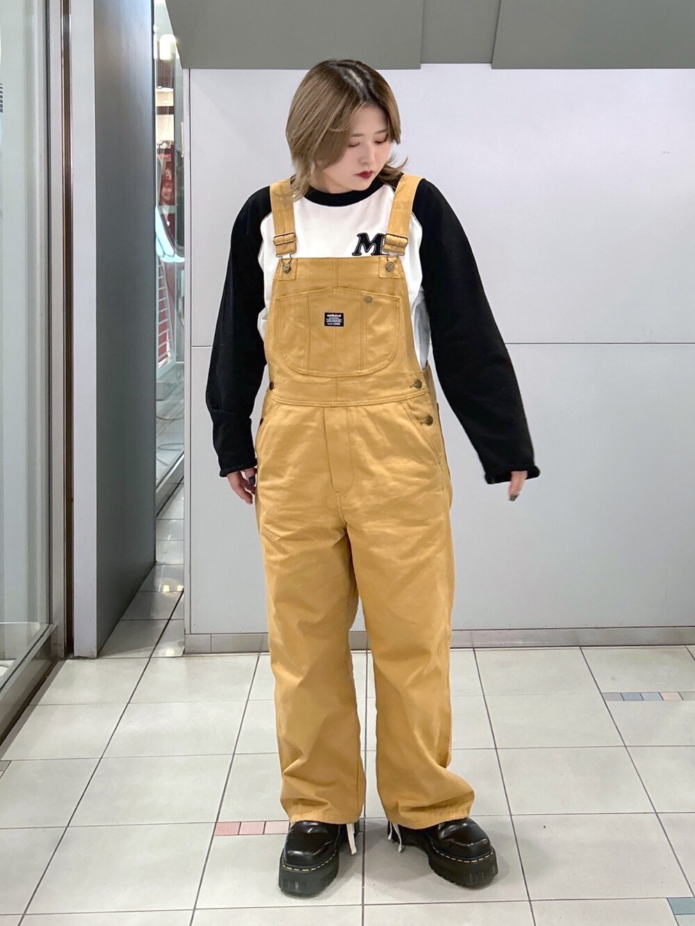 ブラック系のTシャツ/カットソー、ベージュ系のサロペット/オーバーオール、ブラック系のブーツを着用したレディースの冬コーディネートの2枚目の写真