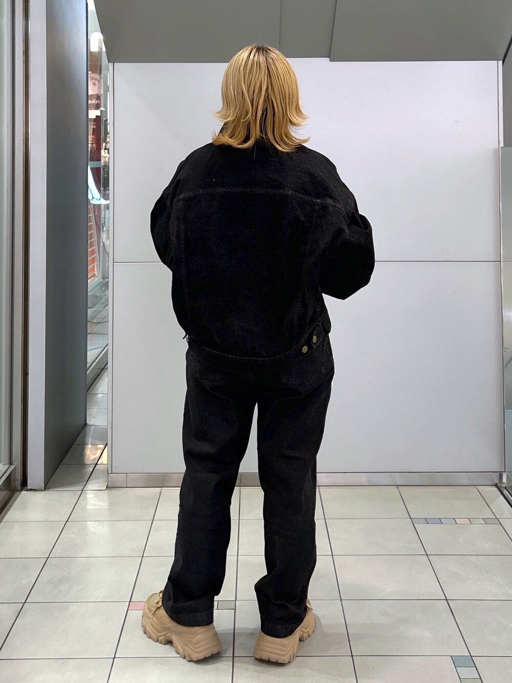 ブラック系のデニムジャケット、グリーン系のTシャツ/カットソー、ブラック系のデニムパンツを着用したレディースの秋コーディネートの4枚目の写真