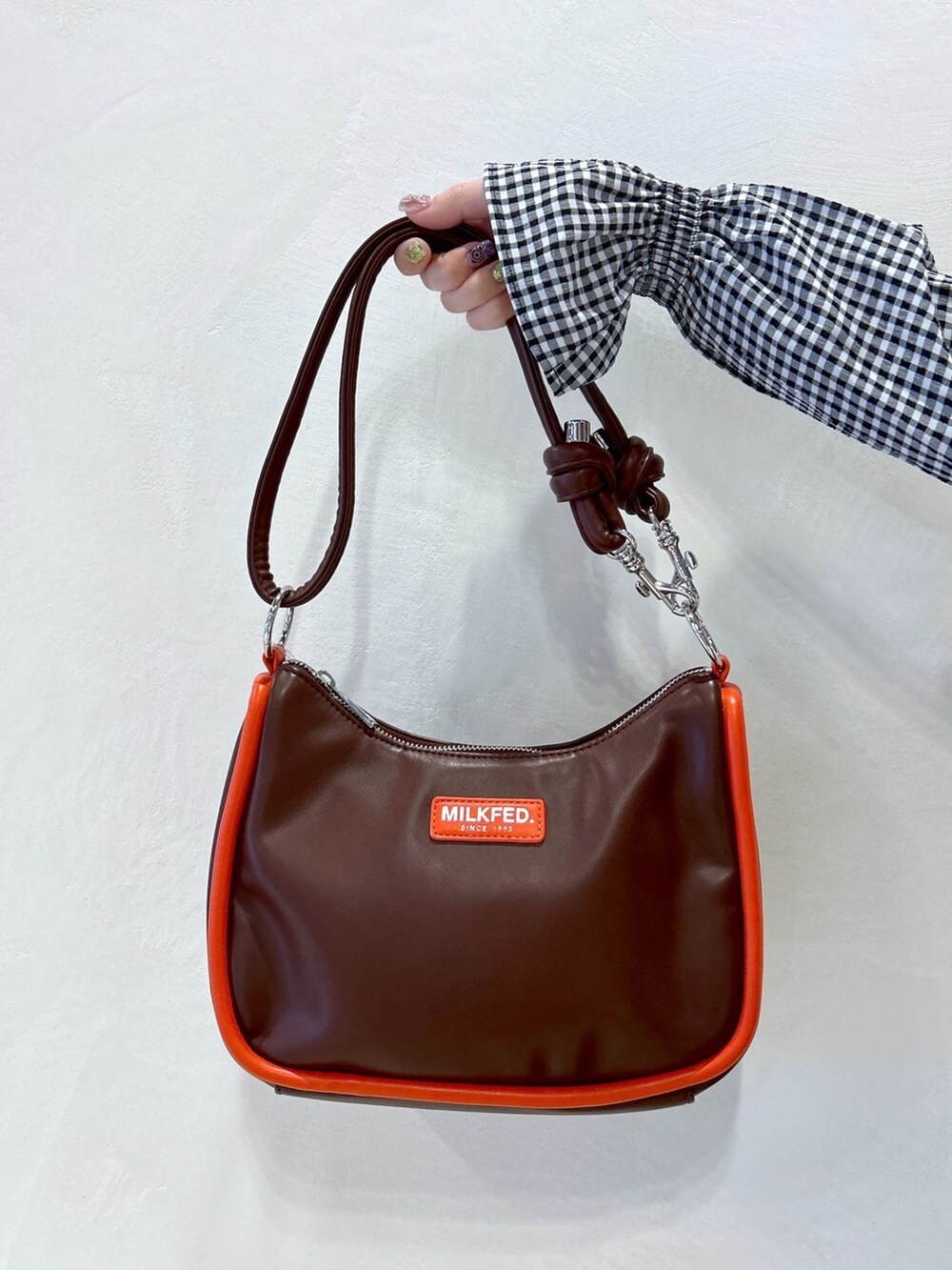 ブラック系のワンピース、ブルー系のデニムパンツ、ブラウン系のショルダーバッグを着用したレディースの春コーディネートの6枚目の写真