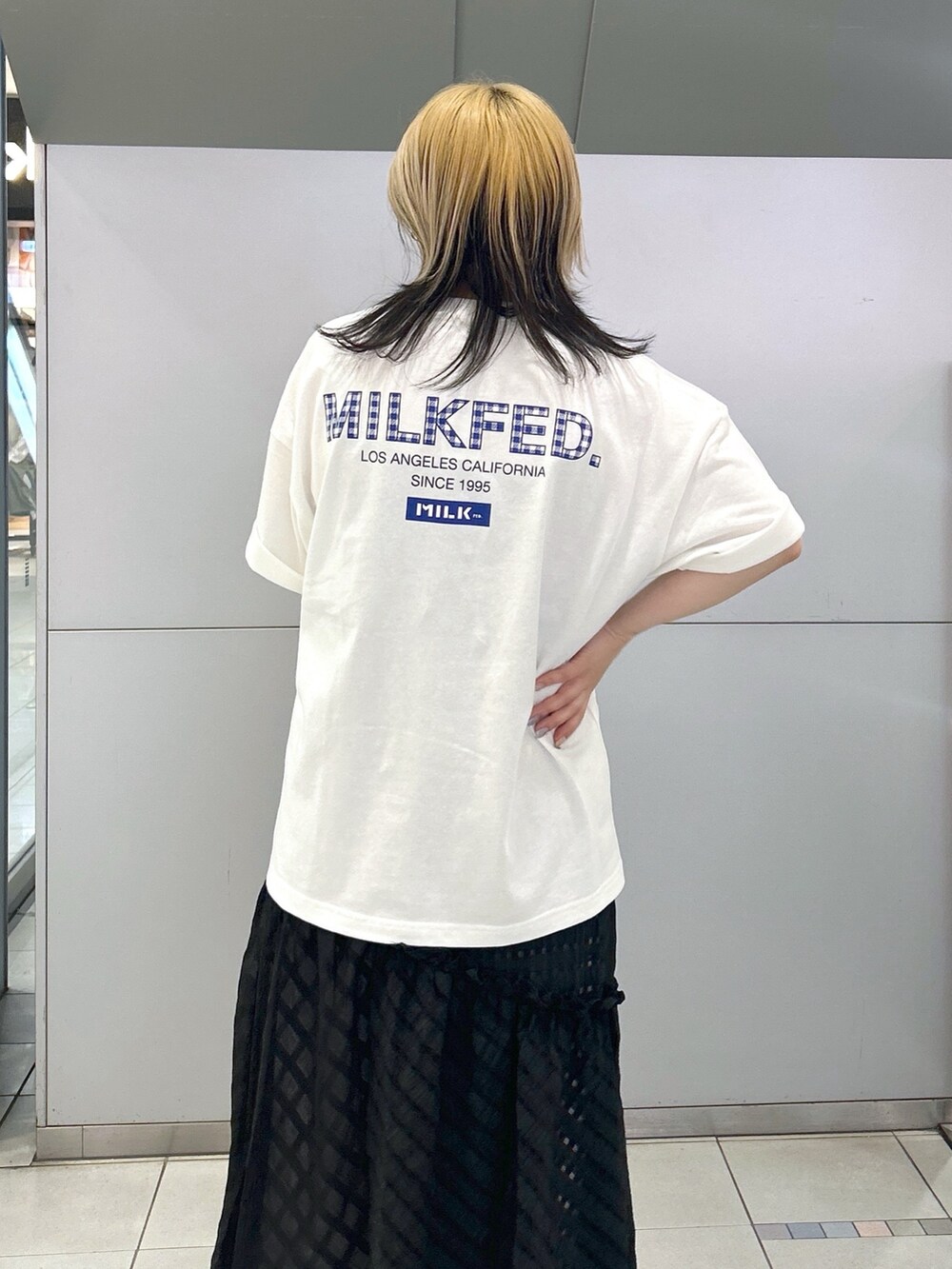ホワイト系のTシャツ/カットソー、ブラック系のスカート、ブルー系のトートバッグを着用したレディースの春コーディネートの4枚目の写真