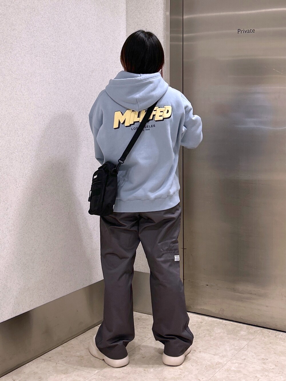 ブルー系のパーカー、ブラック系のショルダーバッグ、グレー系のその他パンツを着用したレディースの夏コーディネートの3枚目の写真