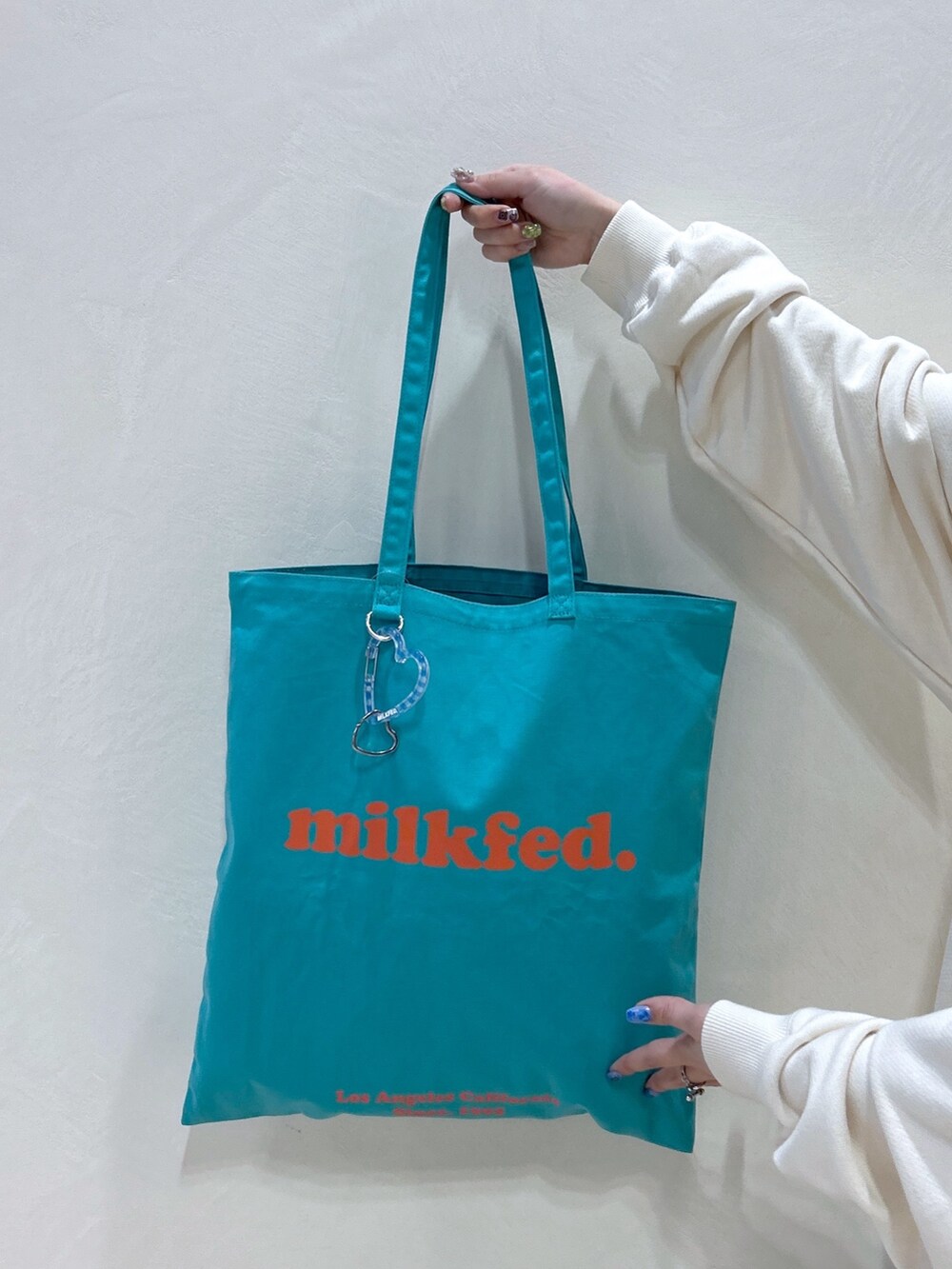 ホワイト系のパーカー、ブラック系のその他パンツ、グリーン系のトートバッグを着用したレディースの春コーディネートの6枚目の写真