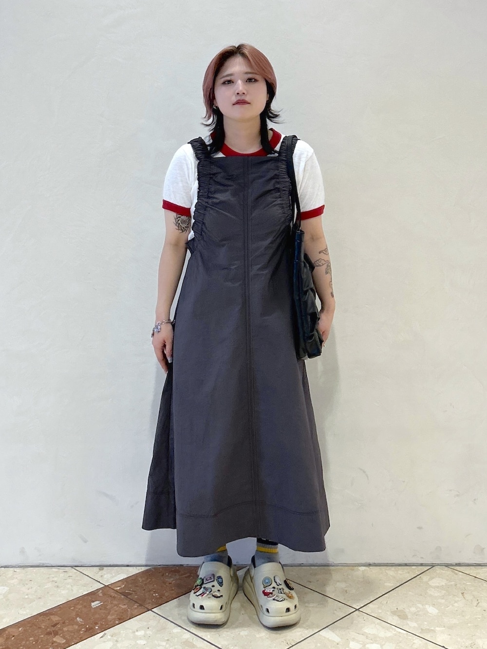 レッド系のTシャツ/カットソー、ベージュ系のサンダル、ブラック系のトートバッグを着用したレディースの春コーディネートの2枚目の写真