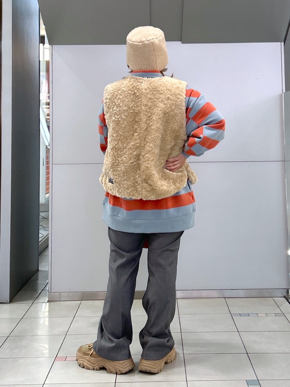 ホワイト系のベスト、ベージュ系のスニーカー、ピンク系のスウェットを着用したレディースの冬コーディネートの2枚目の写真