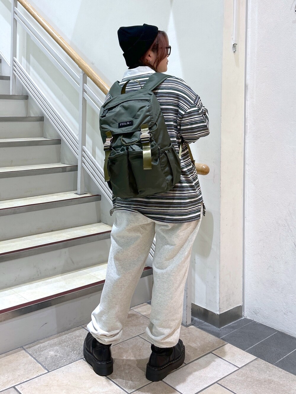 グリーン系のポロシャツ、ベージュ系のスウェットパンツ、グリーン系のバックパック/リュックを着用したレディースの冬コーディネートの5枚目の写真